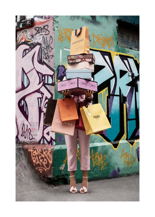  – Fotografi av en kvinne som holder skoesker og handleposer, foran en graffitivegg