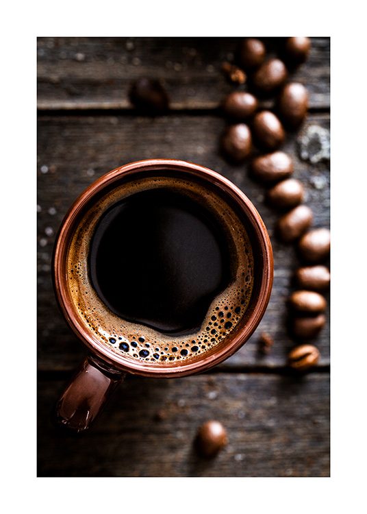  – Fotografi av oversiden av en kaffekopp på et trebord, med kaffebønner ved siden
