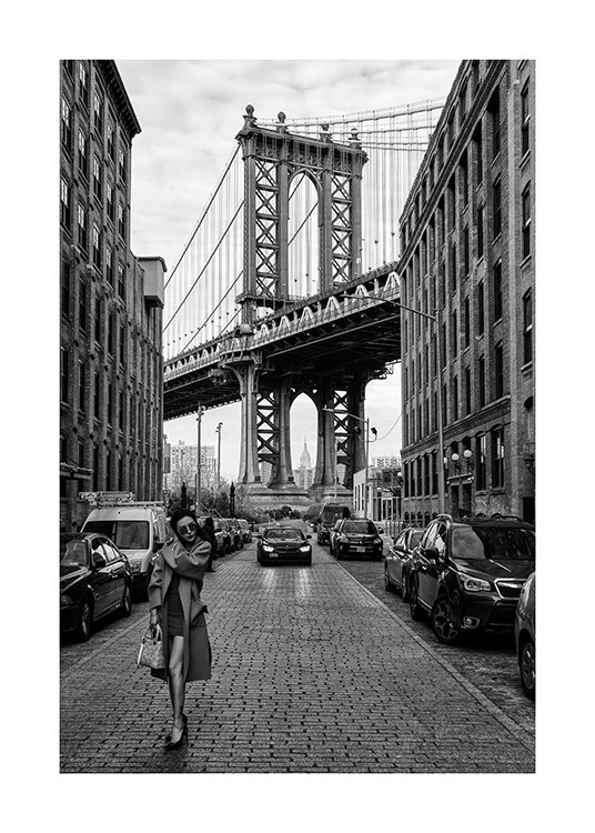  – Svarthvitt-fotografi av en kvinne som står i en gate i New York foran Manhattan Bridge