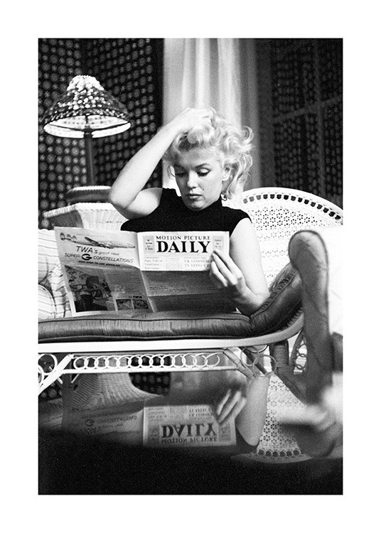  – Svarthvitt-fotografi av ikonet Marilyn Monroe som sitter på sofaen og leser en avis