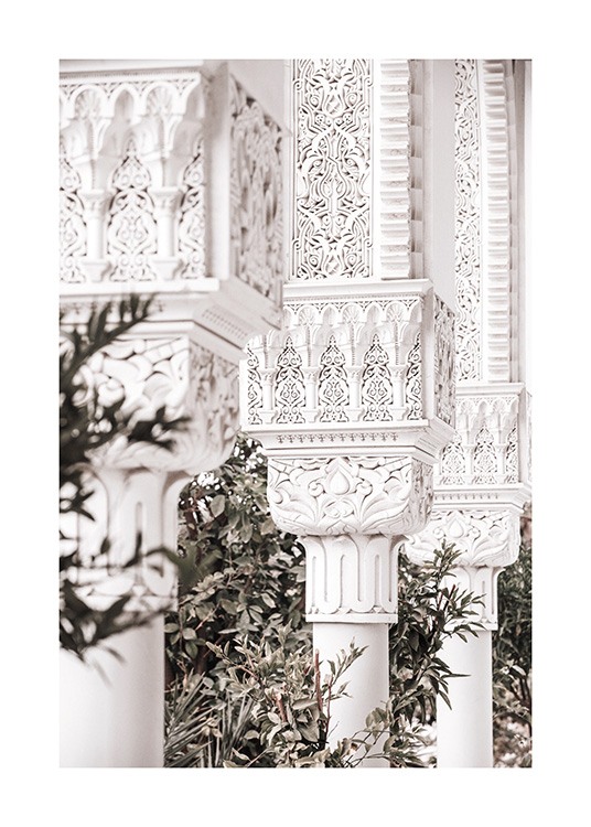  - Fotografi av håndlagde, hvite søyler med mønstre, med grønne blader i bakgrunnen