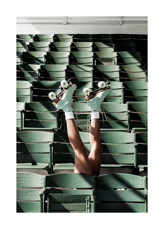 – Fotografi av en person iført rulleskøyter, som strekker beina opp mellom de grønne setene på en stadion