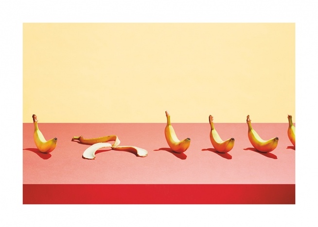  – Fotografi va en rekke med bananer som ligger på et rosa bord mot en gul bakgrunn