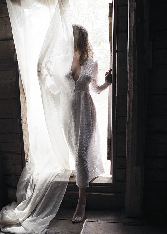  – Fotografi av en kvinne i en døråpning, iført en hvit kjole, dekt av et hvitt forheng