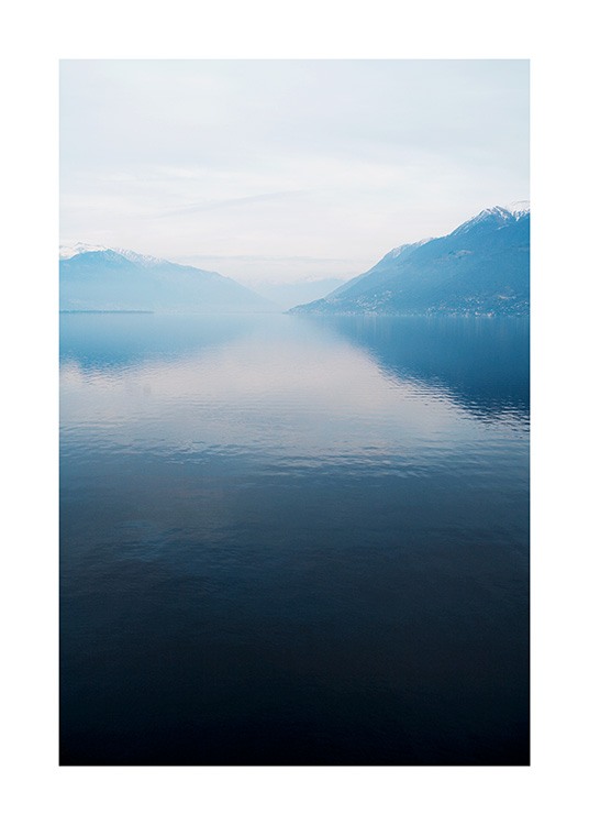 – Fotografi av en innsjø med stille vann, med fjell og tåke i bakgrunnen