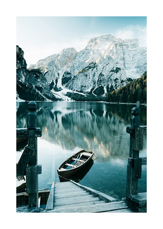 – Fotografi av snødekte fjell bak en innsjø, med en båt og en tretrapp i forgrunnen