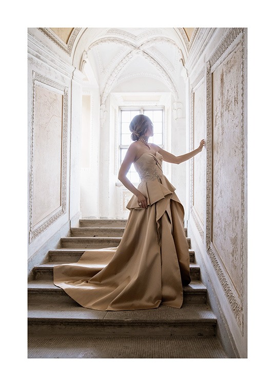  – Fotografi av en kvinne iført en gyllen og beige kjole mens hun står i en trapp i barokkstil