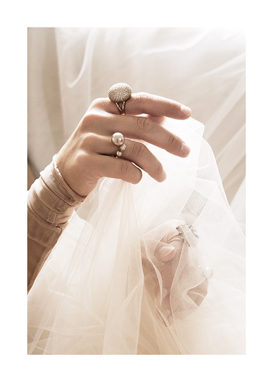  – Fotografi av en kvinne med ringer på fingrene, som holder hvitt tyllstoff i hendene