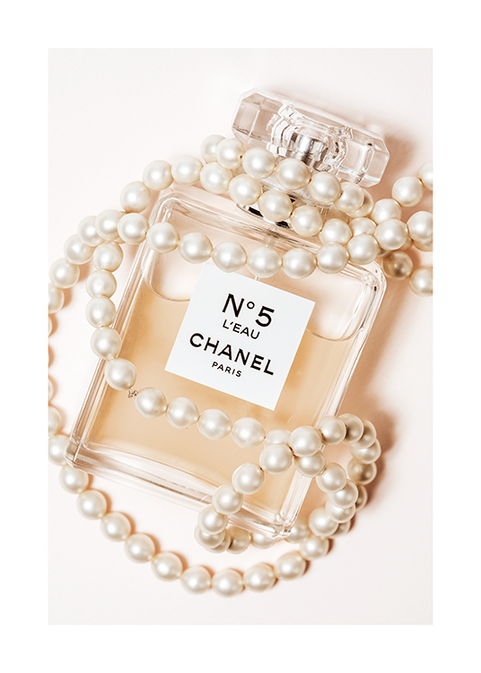  – Fotografi av en parfymeflaske med Chanel No5 skrevet på, pakket inn i et hvitt perlekjede