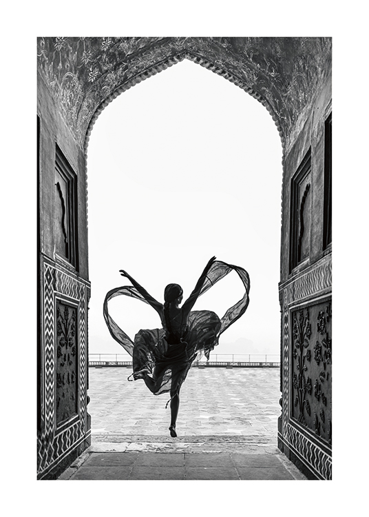  – Svarthvitt-fotografi av en kvinne som danser på ett bein, iført en flagrende kjole, innrammet av en bue