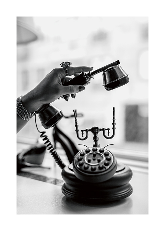  – Et svarthvitt-fotografi av en kvinne som holder en gammel telefon samtidig som hun er iført en unik ring