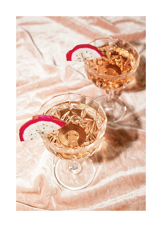  – Et fotografi av to cocktailer med roséchampagne i krystallglass med skiver av dragefrukt