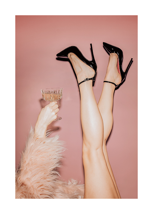  – En kvinne som holder et glass med champagne, iført svarte høyhælte sko og en rosa fuskepels