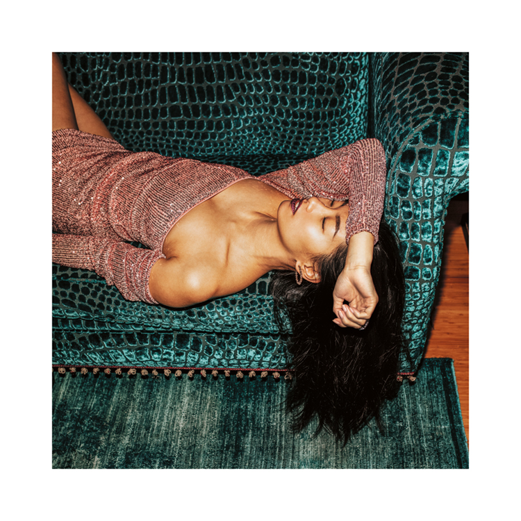  – Et fotografi av en kvinne iført en glitrende kjole, som tar en lur på en turkis sofa