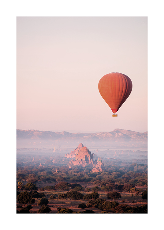  – Fotografi av en rød varmluftsballong i luften, med et fjell og en skog i bakgrunnen