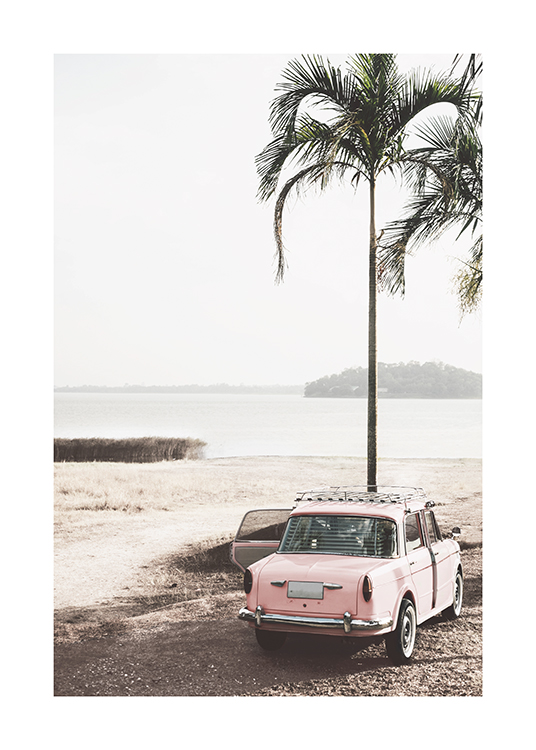  – Fotografi av en rosa veteranbil som står ved siden av en palme på en strand