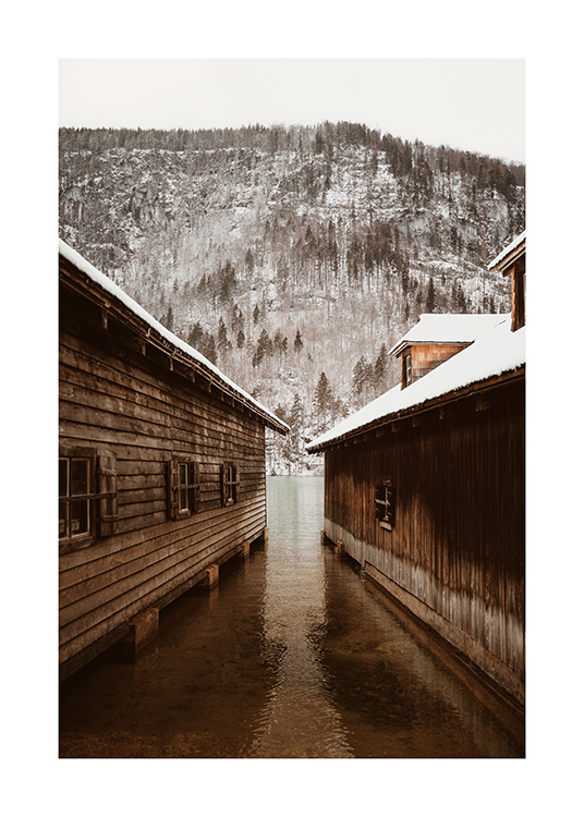  – Fotografi av to båthus foran et fjell med en snødekt skog