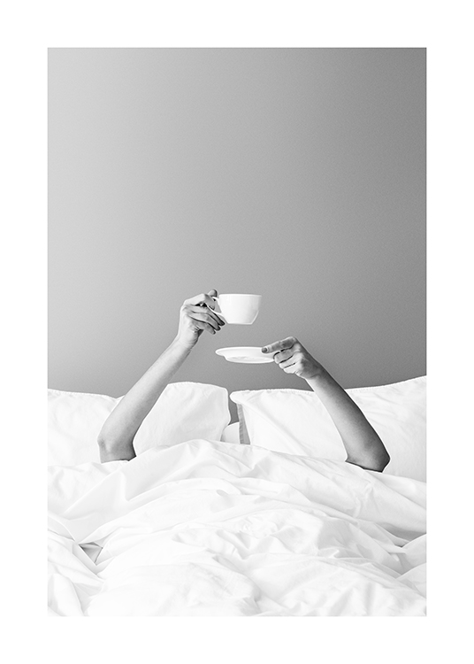 – Svarthvitt-fotografi av en kvinne som holder en kopp med kaffe under dynen i senga